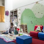 Una mamma gioca con il suo bambino giocano sui tappeti dell'area bimbi presso la biblioteca Renato Nicolini di Corviale.