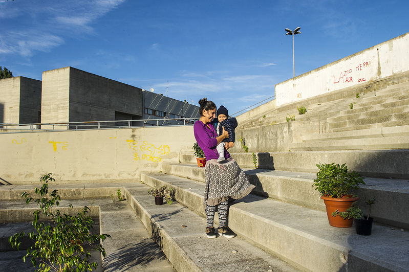Una giovane rom posa con il suo bimbo sugli scalini di Corviale. La ragazza è una volontaria del entro di aggregazione giovanile del quartiere.